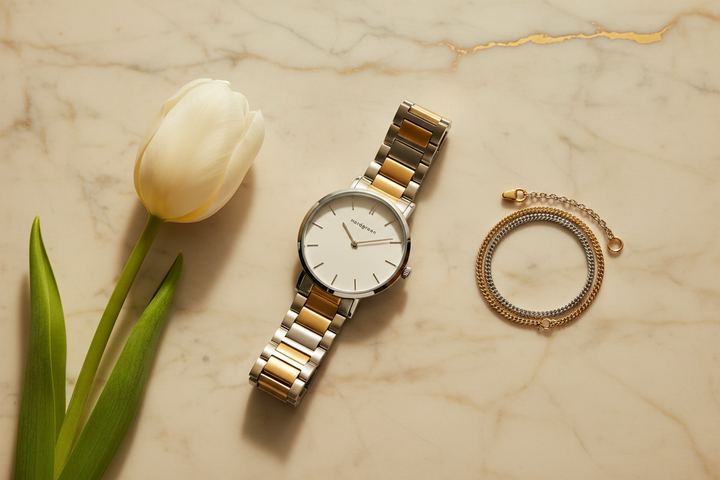 Nordgreen Native 28mm Two-Tone 5-Link Dress Watch flat lay on ivory marble with white tulip